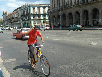 Велосипедист и ретро-автомобили на улицах Гаваны
